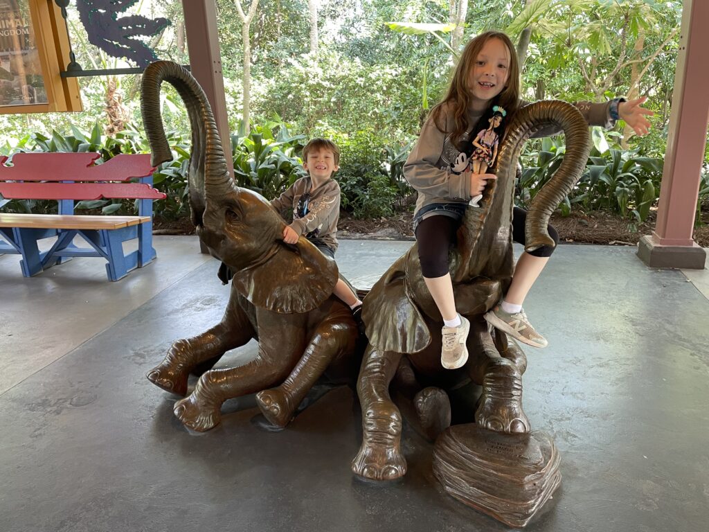 Our daughter and son sitting atop brass statues of elephants at the Conservation Station at Disney's Animal Kingdom.